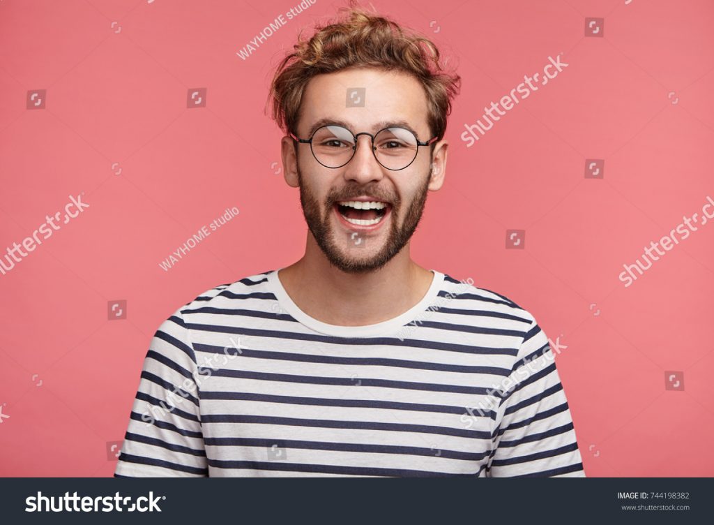 stock-photo-cheerful-hipster-guy-smiles-happily-has-excited-expression-dresssed-casually-celebrates-his-744198382